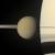 Il tenebroso satellite Titano in primo piano davanti a Saturno e ai suoi anelli